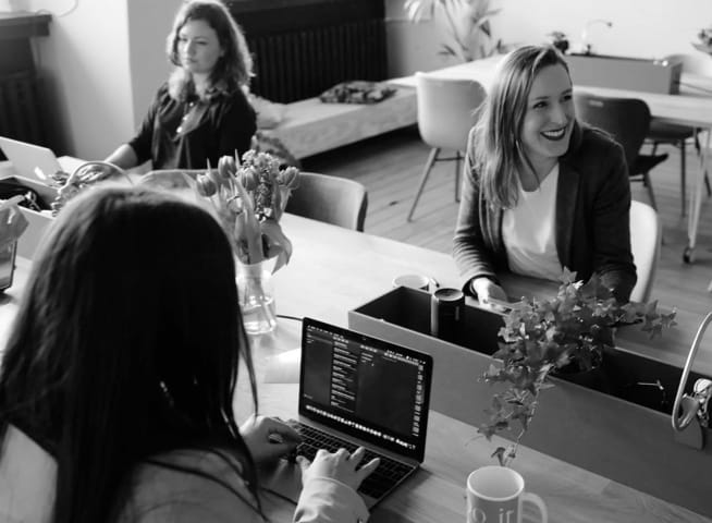 people working on a desk with laptops and coffee